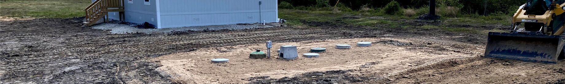 Septic system installation in progress with multiple tank risers exposed in residential yard