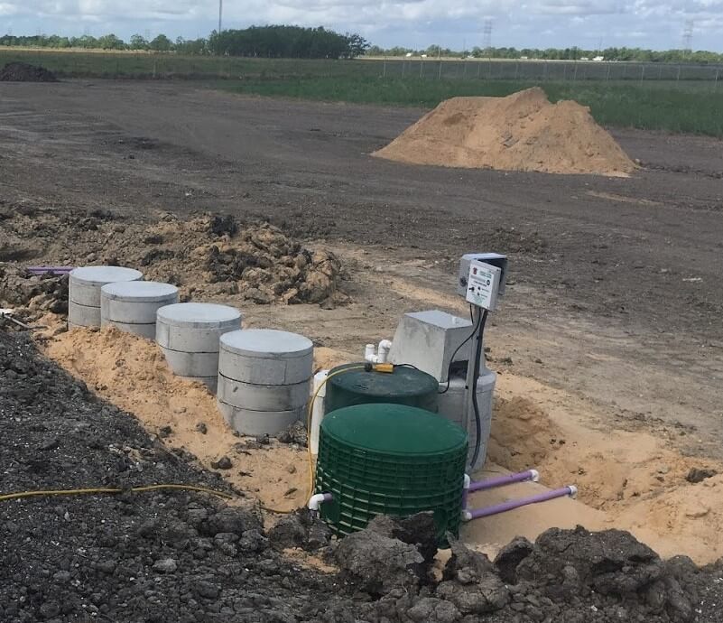 Septic tank system installation in progress with concrete tanks and green cistern on rural jobsite